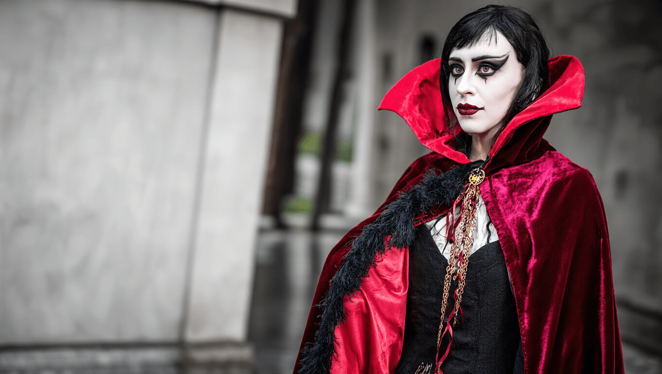 A vampire costume featuring a burgundy velvet cape and dramatic makeup, set against a clean background.
