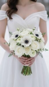 Winter Wedding Flowers That Look Elegant (Not Rustic): Chic & Timeless Floral Ideas for 2026 Elegant white winter wedding bouquet with roses and anemones against a snowy backdrop