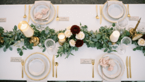 Elegant wedding tablescape featuring a lush eucalyptus and olive garland, blush roses, and ivory candles on ivory silk linen, captured in warm golden hour lighting with a romantic and intimate atmosphere.